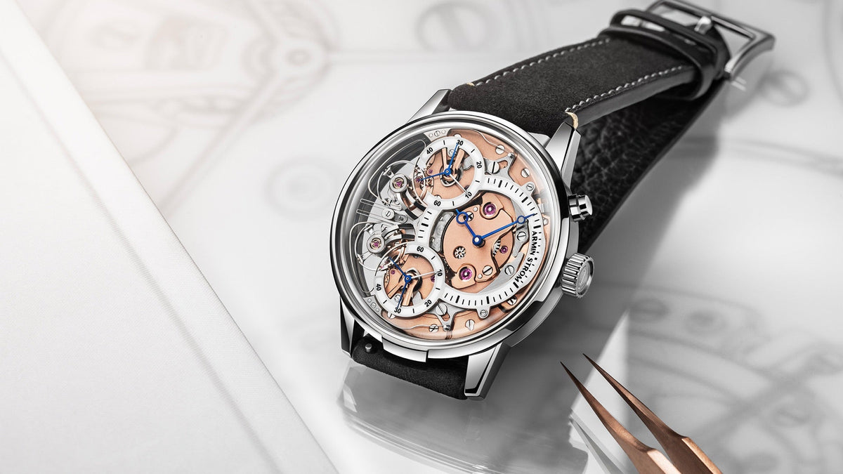 Armin Strom Mirrored Force Resonance Zeitgeist 1665 resting on a watchmaker’s bench with tweezers and a technical drawing