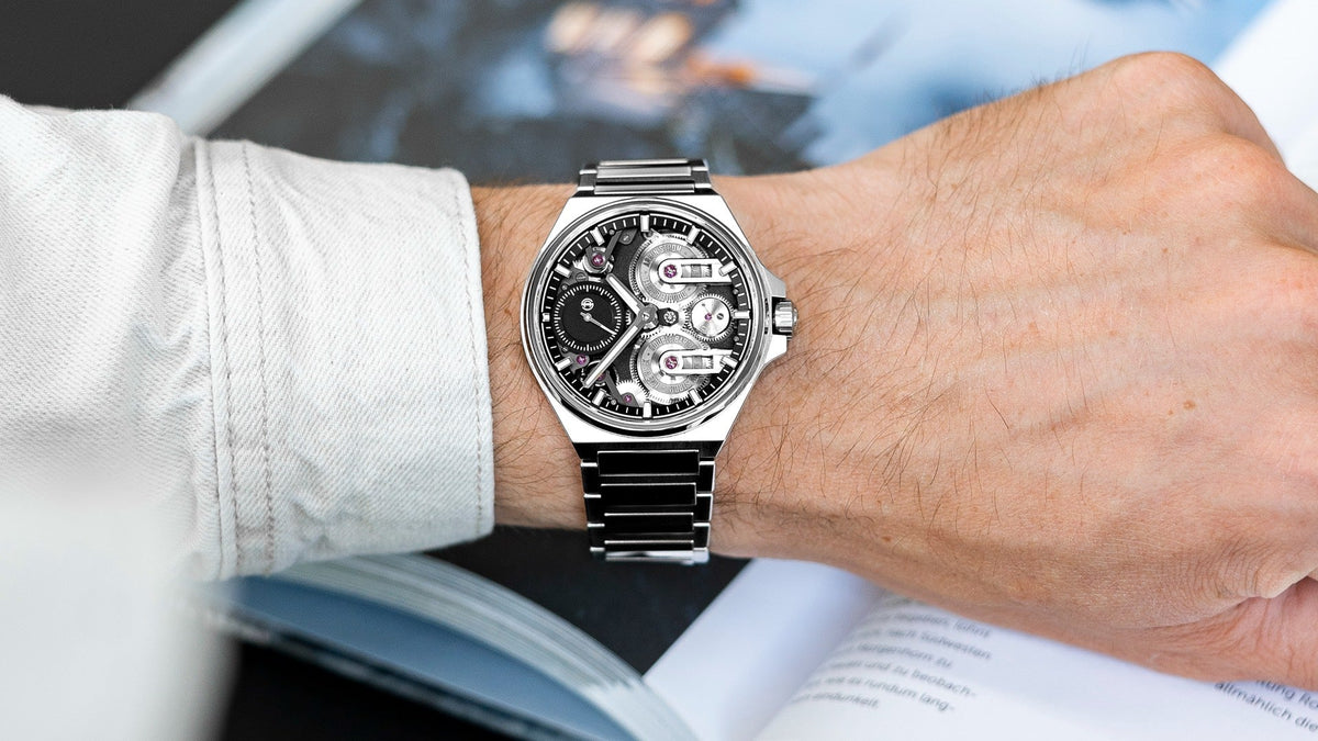 Armin Strom One Week Manufacture Edition worn on the wrist over an open book, steel bracelet and openworked dial