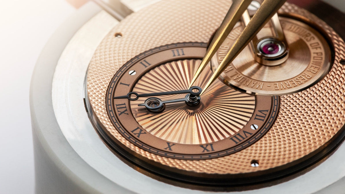 A watchmaker's tweezers set the hands on the rose gold, soleil-guilloché dial of the Armin Strom Tribute³ Au750, in the workshop