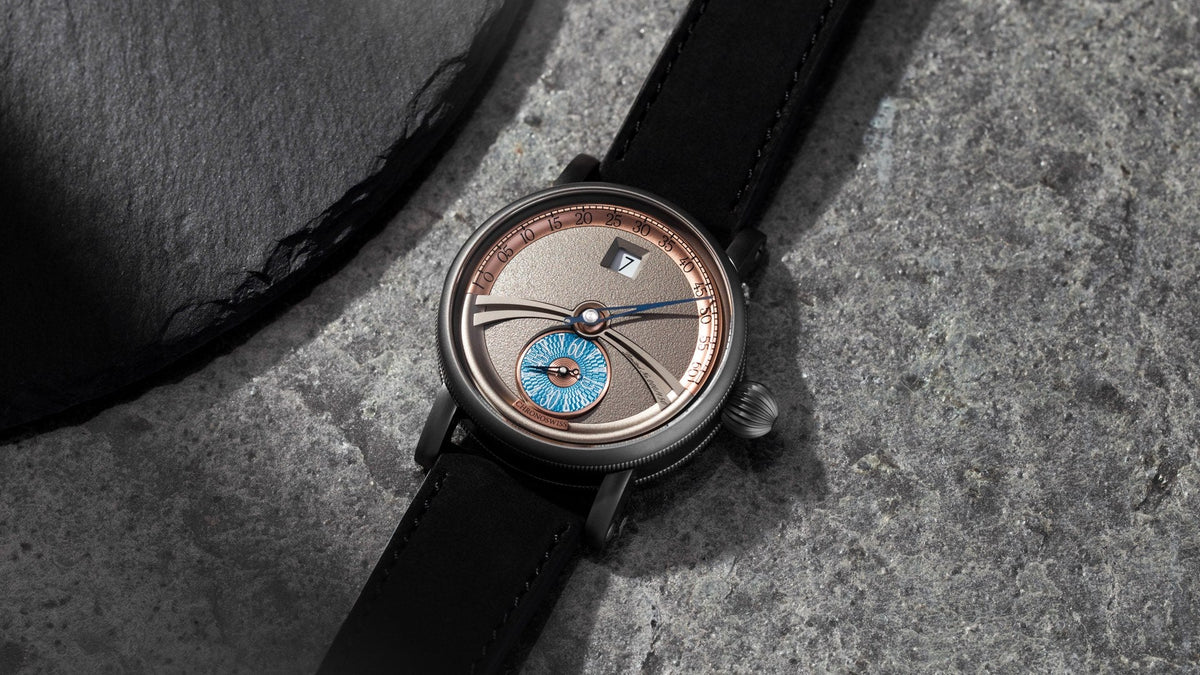 Chronoswiss Delphis Art Deco resting on dark stone, grey dial with blue guilloché seconds