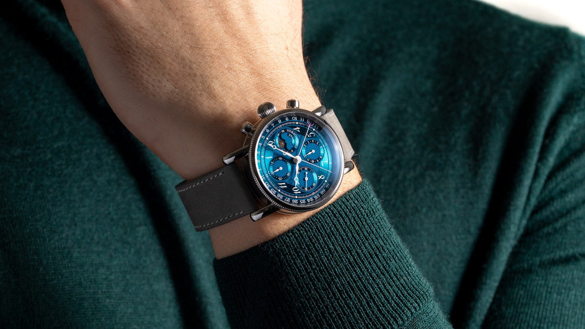 Chronoswiss Lunar Chronograph Aurora worn on the wrist, hand raised to the chin, dark green knit jumper