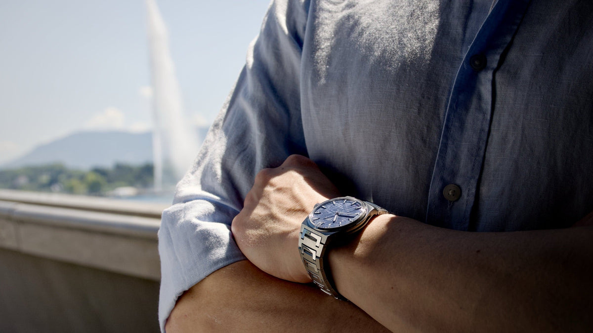 Czapek Antarctique Frozen Meteor worn on the wrist, arms crossed beside Lake Geneva with the Jet d’Eau in the background