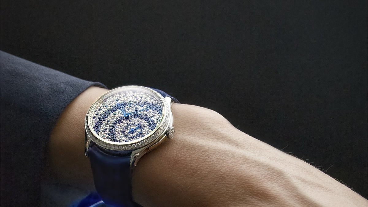 Czapek Promenade Diamond Drops worn on the wrist, resting on a blue glass sculpture