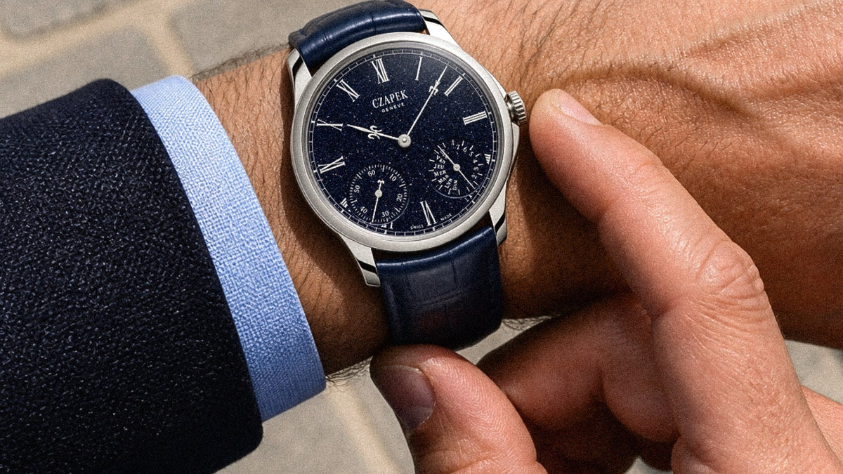 Czapek Quai des Bergues “Midnight in Geneva” worn on the wrist outdoors on stone paving, with a suit and pale blue cuff