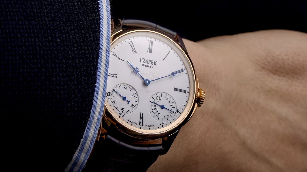 Czapek Quai des Bergues Sursum Corda worn on the wrist, navy blazer sleeve, angled view of the white enamel dial