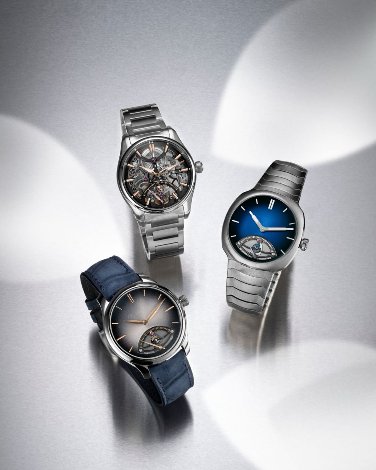 H. Moser & Cie. Pioneer Skeleton, Streamliner and Endeavour Retrograde Seconds together on a grey metal surface
