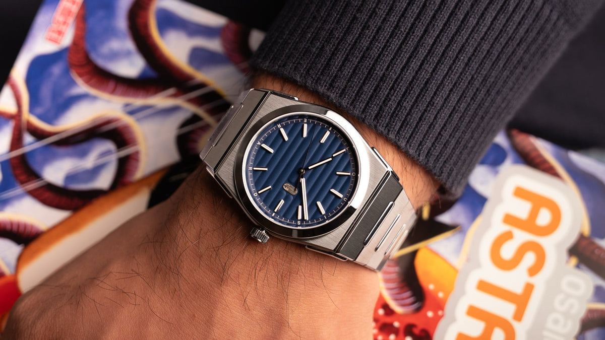 Louis Erard 2340 in Blue worn on the wrist, resting on a comic-book magazine