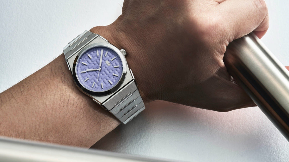 Louis Erard 2340 Mauve worn on the wrist, hand gripping a steel bar