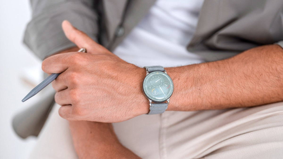 Ressence TYPE 3 EE worn on the wrist, soft green dial on a grey strap