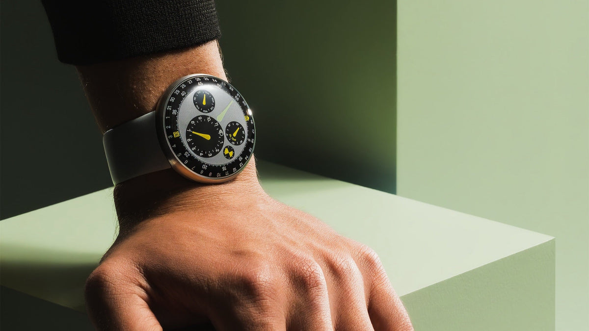 Ressence TYPE 3 MN worn on the wrist, styled green set, grey-blue rubber strap
