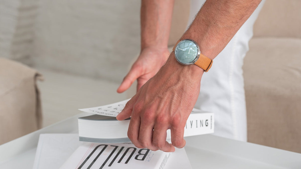 Ressence TYPE 8 S worn on the wrist while a hand reaches for a book