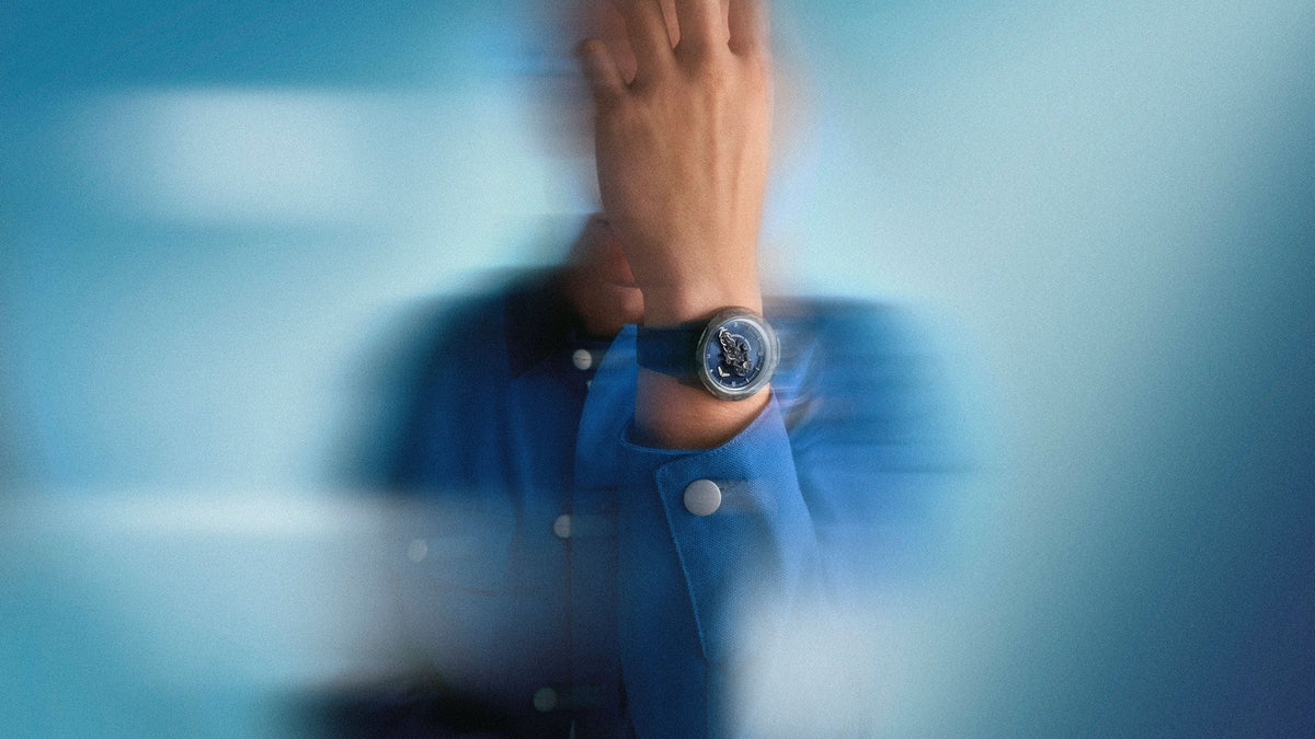 Ulysse Nardin Freak ONE NAVY BLUE worn on the wrist, blue dial and Carbonium bezel against a blue blur