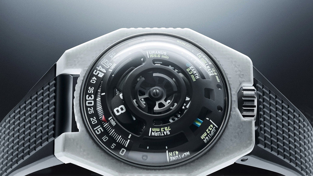 URWERK UR-100V LS Ceramic resting on a reflective surface, white ceramic case and black rubber strap
