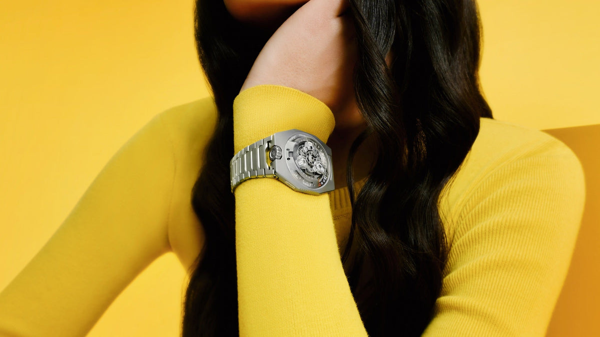 URWERK UR-100V Magic T on the wrist of a woman in a yellow sweater, titanium case and bracelet