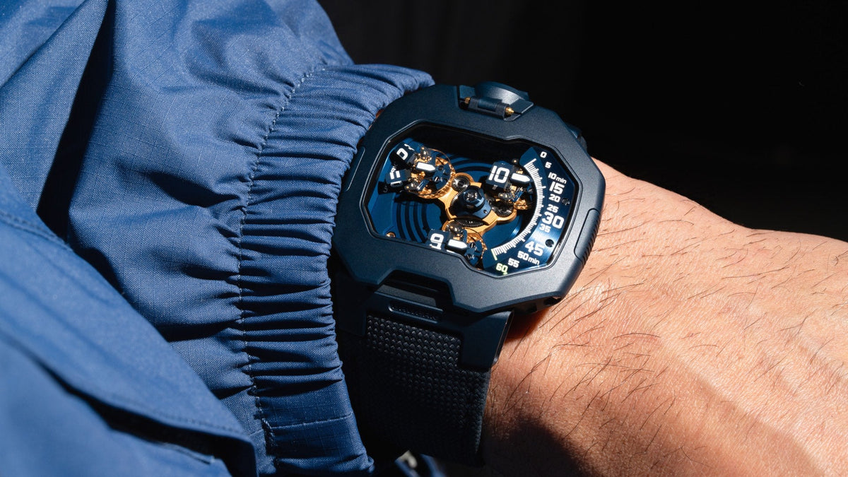 URWERK UR-120 Blue Planet on the wrist, deep blue display with gold-coloured satellite parts, blue sleeve beside it
