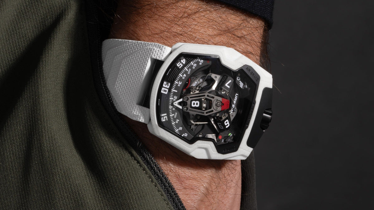URWERK UR-230 Polaris on the wrist, white ceramic case and white rubber strap, hand resting in an olive pocket